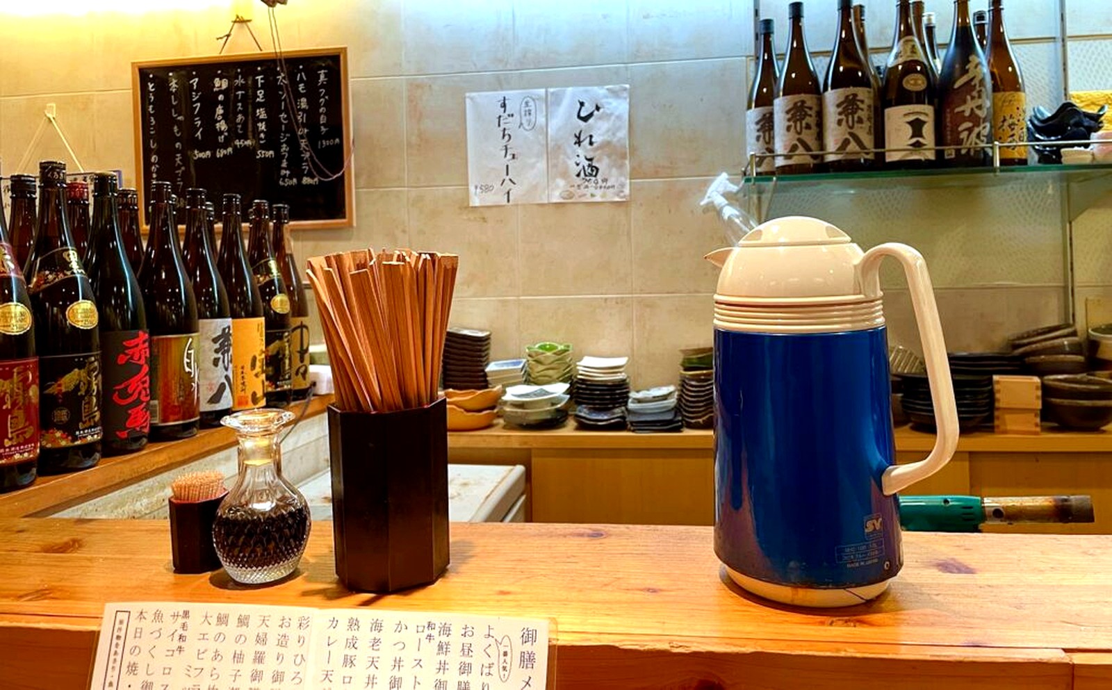 日本酒の瓶や割り箸が並ぶ旬彩食卓ひろのカウンター席