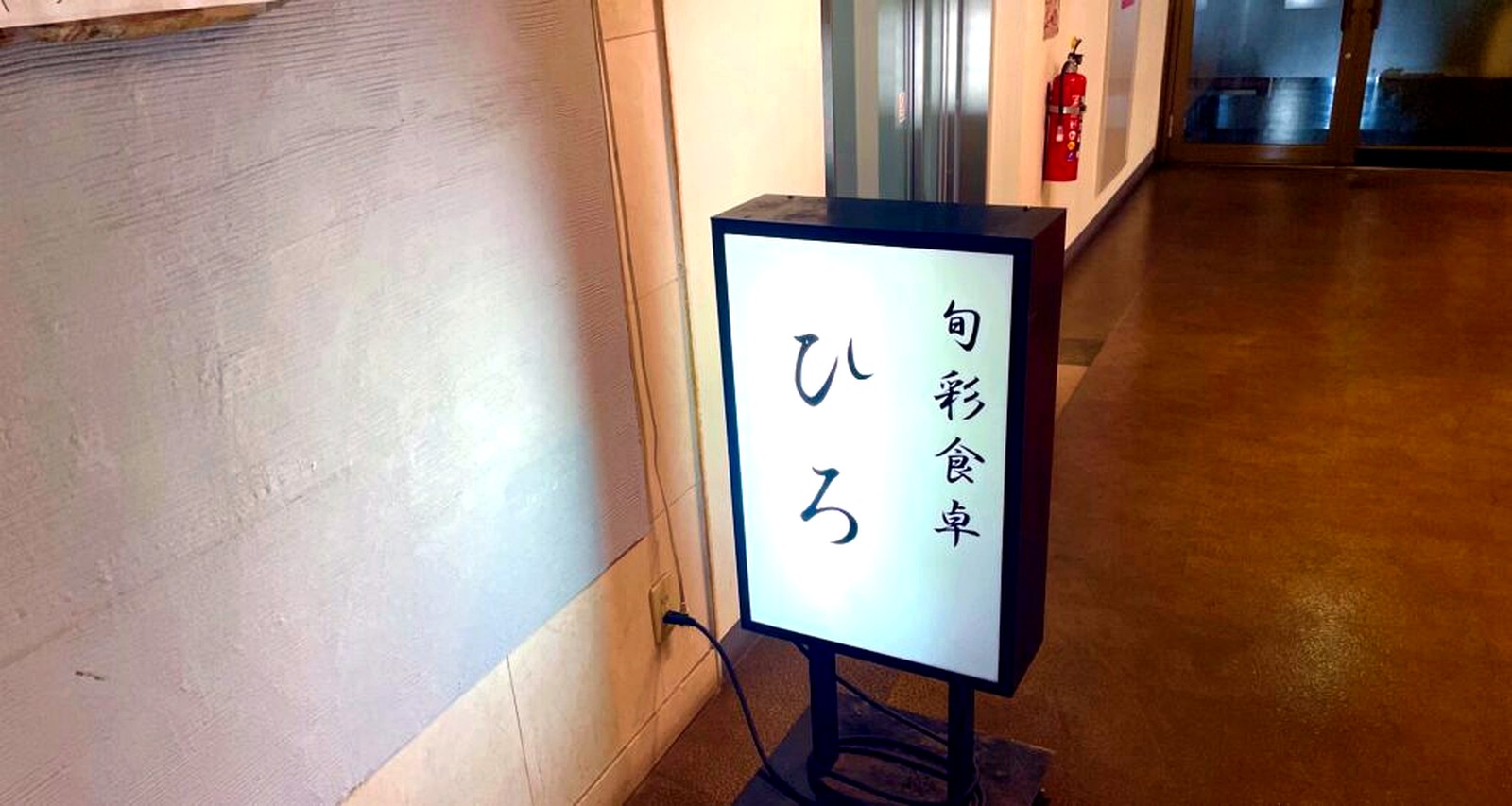 ラポルテ西館2階の廊下に立つ旬彩食卓ひろの光る看板