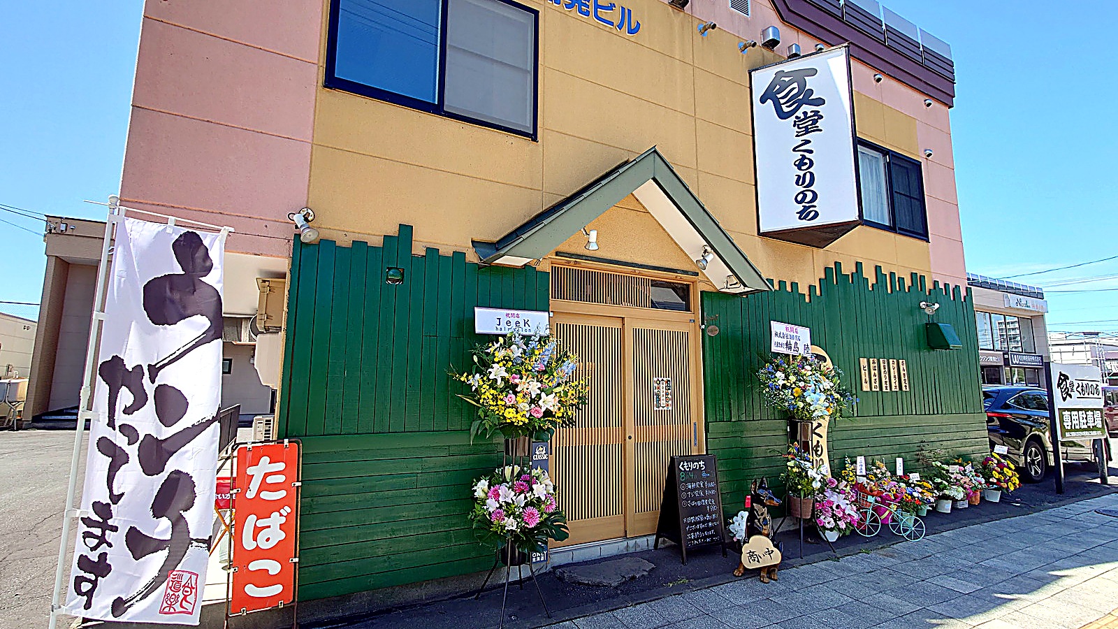 北海道旭川市「食堂くもりのち」の店頭外観 開店祝いの花が並ぶ晴れた日の様子